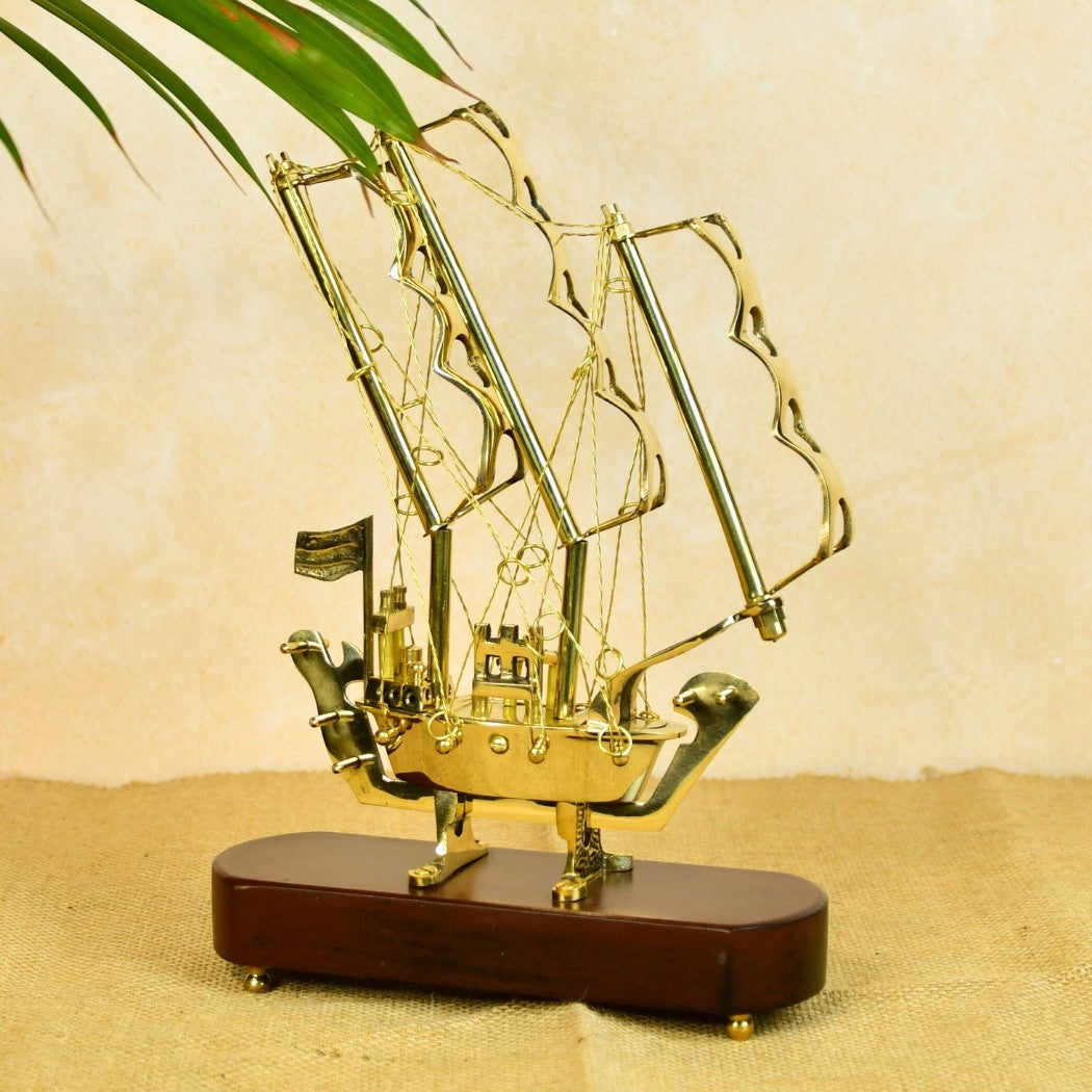 Handcrafted brass decorative pieces shaped like a vintage sailing ship with detailed sails on a wooden base
