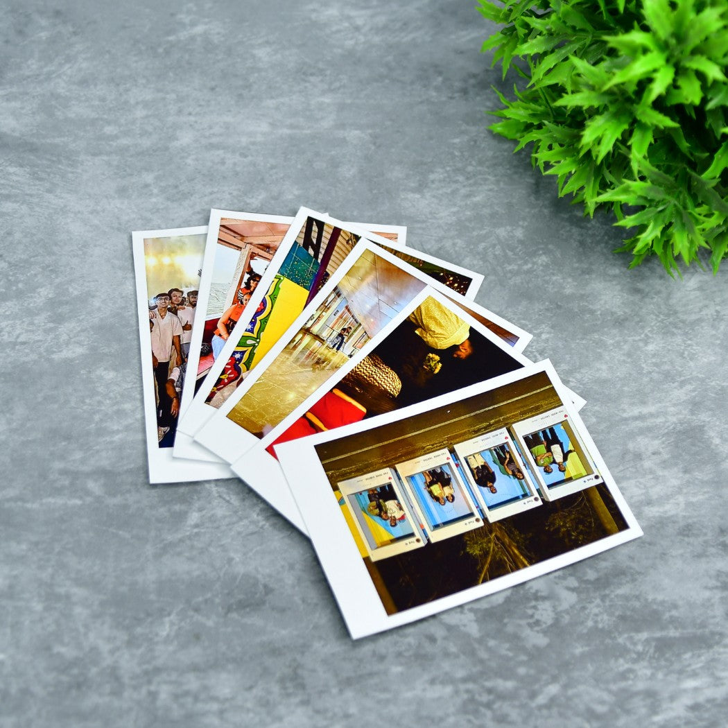 Decorative polaroid prints fanned out on gray surface with green plant in background