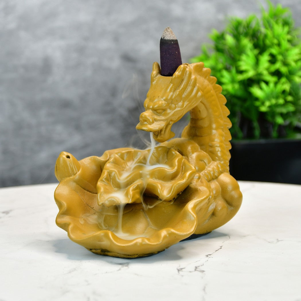 Gold dragon smoke fountain incense burner made of resin on marble table with plant background